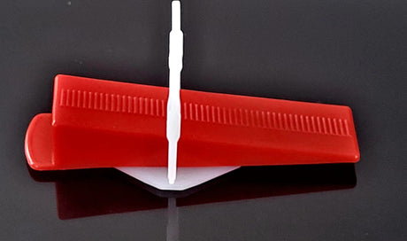 Weiße Zuglasche und roter Fliesenkeil des MB Leveling Keilsystems zusammen im Detail